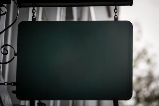 An empty horizontal green rectangular sign hanging on the exterior of a Dutch shop in the Netherlands. The bold color and minimalist look draw attention, offering ample space for custom content.