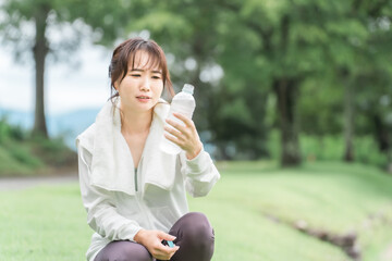 運動の休憩に水分補給をするアジア人女性
