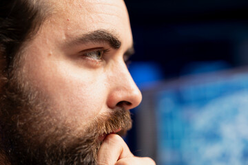 Focus on engineer using PC in blurry background to maintenance artificial intelligence neural networks. Remote IT employee doing checkup on AI systems, close up on face