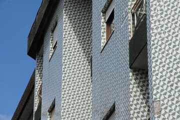 Building facade in Braga, Portugal. Geometric tile pattern in vibrant blue, white, and gray hues. Intricate design resembling abstract art piece. Striking modern architectural detail.