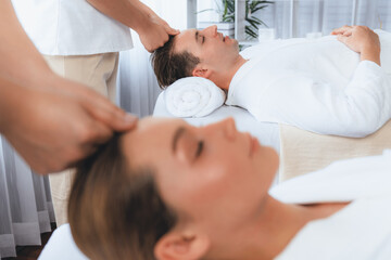 Fototapeta premium Caucasian couple enjoying relaxing anti-stress head massage and pampering facial beauty skin recreation leisure in dayspa modern light ambient at luxury resort or hotel spa salon. Quiescent