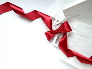 White paper bags tied with shiny red satin bow on white background