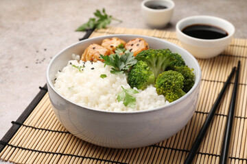 Tasty rice with broccoli and chicken served on grey table, closeup