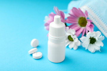 Allergy treatment. Nasal drops, pills and flowers on light blue background, closeup. Space for text