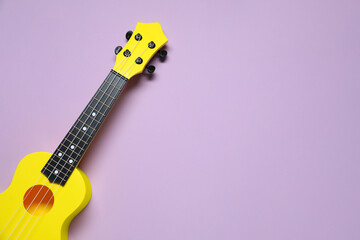 One ukulele on violet background, top view. Space for text