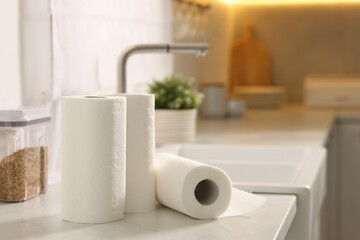 Rolls of paper towels on white marble countertop in kitchen, space for text
