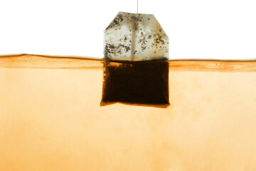 Putting tea bag into glass cup on white background, closeup