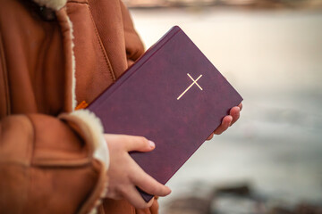 A woman holds the Bible in her hands in nature. Christianity concept.