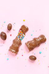 Chocolate Easter bunnies with eggs and sprinkles on pink background