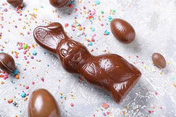 Chocolate Easter bunny with eggs and sprinkles on grunge background, closeup