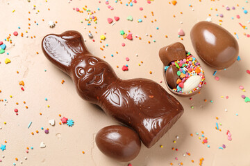 Chocolate Easter bunny with eggs and sprinkles on beige background