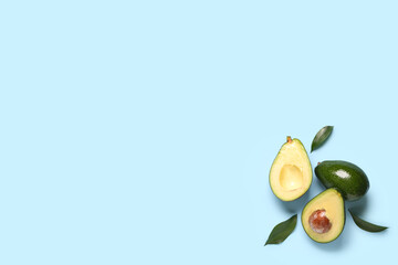 Fresh ripe avocados and leaves on blue background