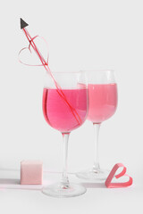 Glasses of tasty cocktail with straw and ring box on white background. Valentine's Day celebration