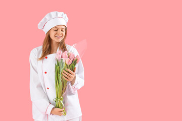Young female chef with bouquet of tulips on pink background. International Women's Day celebration
