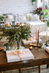 Elegant celebration setup with beautifully wrapped gifts, greenery, and candles on a wooden table