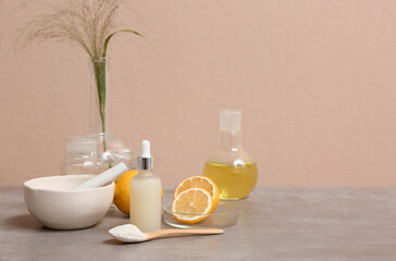 Laboratory glassware with ingredients and samples for preparing natural cosmetics on grey table near beige wall