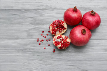 Fresh ripe pomegranates with seeds on grey wooden background