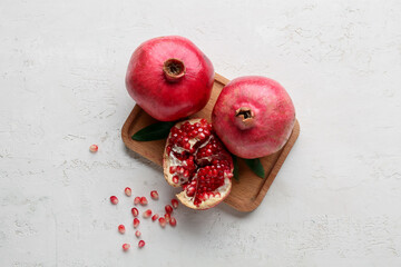 Wooden board with fresh ripe pomegranates and seeds on white background