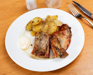 Rabbit thigh, stewed with potatoes and spices. Hearty homemade dinner served with light white sauce and bran bread. Rabbit meat baked until golden brown with potato segment