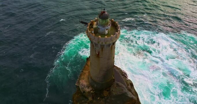 A rotating overhead shot of Phare du Four a lighthouse in Bretagne France. An ancient one standing far from the shore in the ocean and the first to meet huge waves