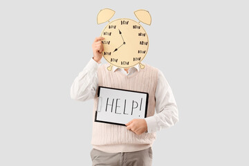 Young man holding clipboard with word HELP and paper alarm clock on light background. Time management concept