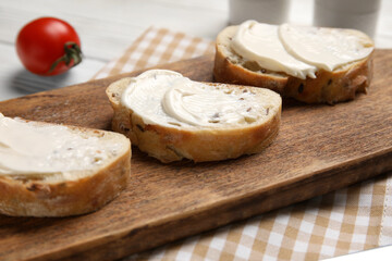 Cutting board of tasty bruschetta with processed cheese and fresh tomato on white wooden background, closeup