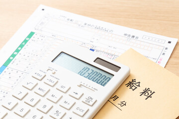 机に置かれた確定申告書類と電卓と給料袋