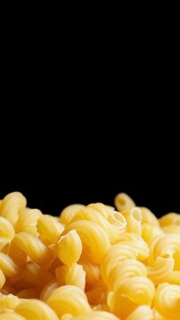 Raw cavatappi pasta rotate in black background.