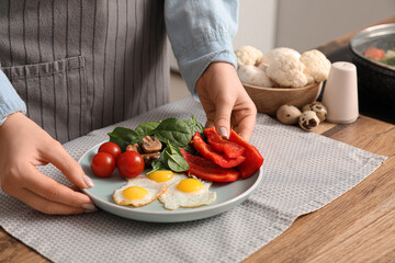 Woman preparing tasty dinner with fried quail eggs and fresh vegetables kitchen, closeup