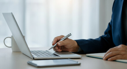 Fototapeta premium A man is writing on a laptop with a pen
