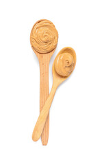 Wooden spoons with tasty peanut butter on white background