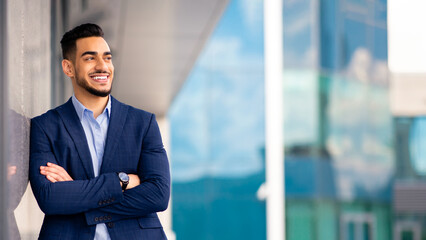 Happy millennial bearded arab man in suit wealthy businessman or CEO standing next to modern...