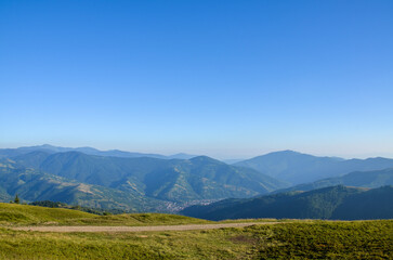 Summer view showcasing rolling green mountains under a bright and clear blue sky. Ideal for...