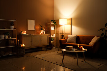 Interior of dark living room with sofa, shelf units and burning candles