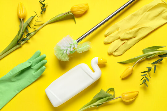 Cleaning supplies with spring flowers on yellow background