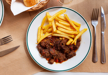 Wild boar with spicy sauce served with french fries on plate
