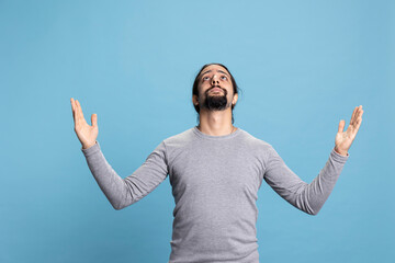 Naklejka premium Spiritual adult showing belief and faith in Jesus Christ asking for forgiveness, hopeful guy worshipping the Lord. Young person being emotional and wishful, pleading in meditation and Christianity.