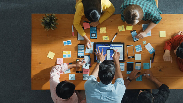 Top down view of business team writing idea on sticky note while planing for Ux Ui design for mobile phone interface. Group of creative designer working on wireframe prototype design. Convocation.