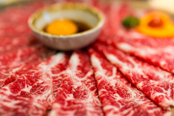 Premium wagyu beef meat served with egg yolk for cooking sukiyaki or yakiniku in Japanese restaurants.