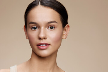 Natural beauty portrait of a young woman with light skin, soft makeup, and a neutral background...