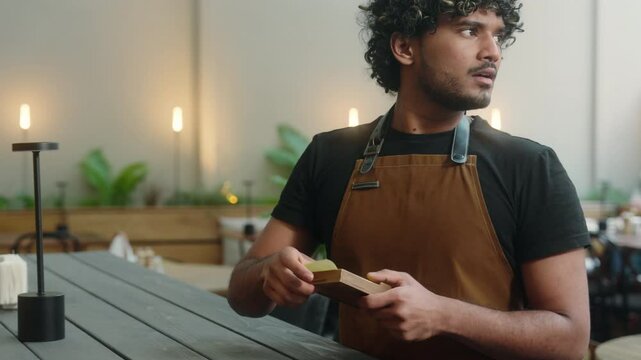 Sad man Indian Arabian guy waiter in apron cafe worker cleaner male business owner latino barista working in cafe restaurant serving no money cash tips bill payment dissatisfied worried upset service