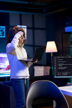 Stressed programmer trying to fix vulnerabilities in software systems using notebook, suffering headache. Tired woman feeling pain from fatigue, using laptop to patch security exposures