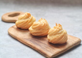 Kue Sus Isi Vla or soes cake (Choux Pastry Cream Puff) is Crispy and airy choux pastry shell are filled with smooth and soft custard cream. served in a plate.
