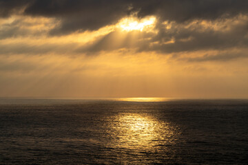 Dark cloudscape over the vast ocean with calm and sparkling reflections on the water.