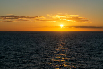 Fototapeta premium Bright sun in the sunset hours over the Pacific horizon with shimmering water reflections.