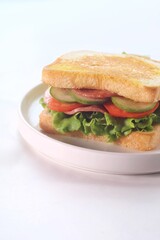 sandwich with smoked beef, lettuce, cucumber and tomato on white plate, isolated on white background. 
