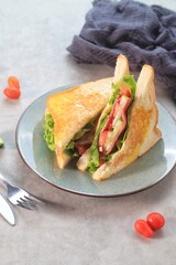 Sandwich cut in half. Two pieces of delicious smoked beef sandwich with lettuce, tomatoes and sauce. 