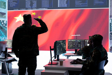 Chinese military officer in uniform monitors critical data on big screen. The national flag is presented in the army operations room, military command center used for propaganda.