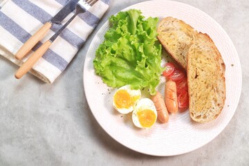 Sourdough bread open faced sandwiches with lettuce, tomatoes, egg and sausage. A healthy and delicious breakfast.
