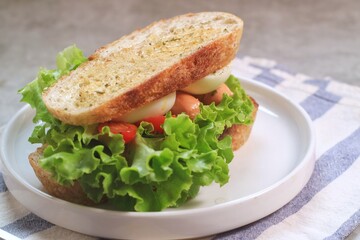 Sourdough bread open faced sandwiches with lettuce, tomatoes, egg and sausage. A healthy and delicious breakfast.
